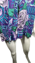 Load image into Gallery viewer,  A medium vintage Partners Mervyns short sleeve button up with a purple and blue all-over floral print. The shirt is missing all of the buttons but one and has been well-worn. Measured FlatChest - 36&quot;Sleeve - 9&quot;Length - 28&quot;