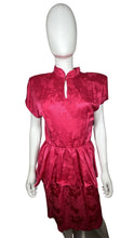 Load image into Gallery viewer, An 80’s vintage bright pink peplum dress with floral print on the silk. Measured Flat Chest- 32” Waist- 26” Hips- 36” Length- 41”