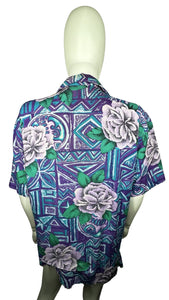 A medium vintage Partners Mervyns short sleeve button up with a purple and blue all-over floral print. The shirt is missing all of the buttons but one and has been well-worn. Measured FlatChest - 36"Sleeve - 9"Length - 28"