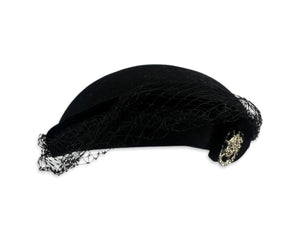 This pillbox hat is a vintage gem, featuring a black velvet design and adorned with a silver and rhinestone brooch. It's Union made and comes in its original box.