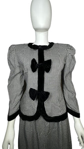 This posh Vintage Jessica Howard by Mitchell Rodbell suit features a charming houndstooth blazer with shoulder pads and a matching skirt. Measurements when laid out flat include 32" for the top chest and 21" for the sleeves, with a length of 23". The bottom waist measures 26" and the hips are a generous 44" with a length of 31".