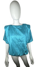 Load image into Gallery viewer, Get ready to add some retro flair to your wardrobe with this Vintage Novelle 80s Teal Blouse! Featuring a stretch waist band and shoulder pads, this blouse will give you a bold and unique look. When laid flat, it measures 42&quot; at the chest and has a len...