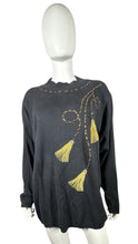 Load image into Gallery viewer, Experience the ultimate blend of style and comfort with our Vintage AfterShock Sweatshirt. This black long sleeve has been beautifully crafted with gold embellishment, embroidered tassels, and shoulder pads. Measured at 46&quot; for the chest, 25&quot; for the s...