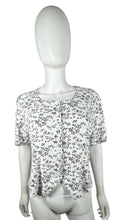 Load image into Gallery viewer, Experience a touch of nostalgia with our Vintage Black and White Floral Crop Top - the perfect blend of old and new. This short sleeve button-up piece features a chest measurement of 34&quot; and a length of 19&quot;, giving you a flattering fit.