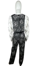 Load image into Gallery viewer, Introducing a one-of-a-kind black and white floral jumpsuit from the 80&#39;s, complete with a stretch waist for ultimate comfort. Measurements include: Chest - 39&quot;, Sleeve - 24&quot;, Waist - 26&quot;, Hips - 40&quot;, Inseam - 28&quot;, Length - 60&quot;. Don&#39;t miss this rare vi...