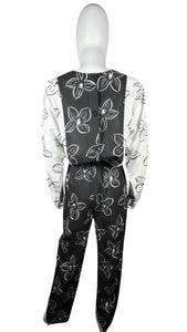 Introducing a one-of-a-kind black and white floral jumpsuit from the 80's, complete with a stretch waist for ultimate comfort. Measurements include: Chest - 39", Sleeve - 24", Waist - 26", Hips - 40", Inseam - 28", Length - 60". Don't miss this rare vi...