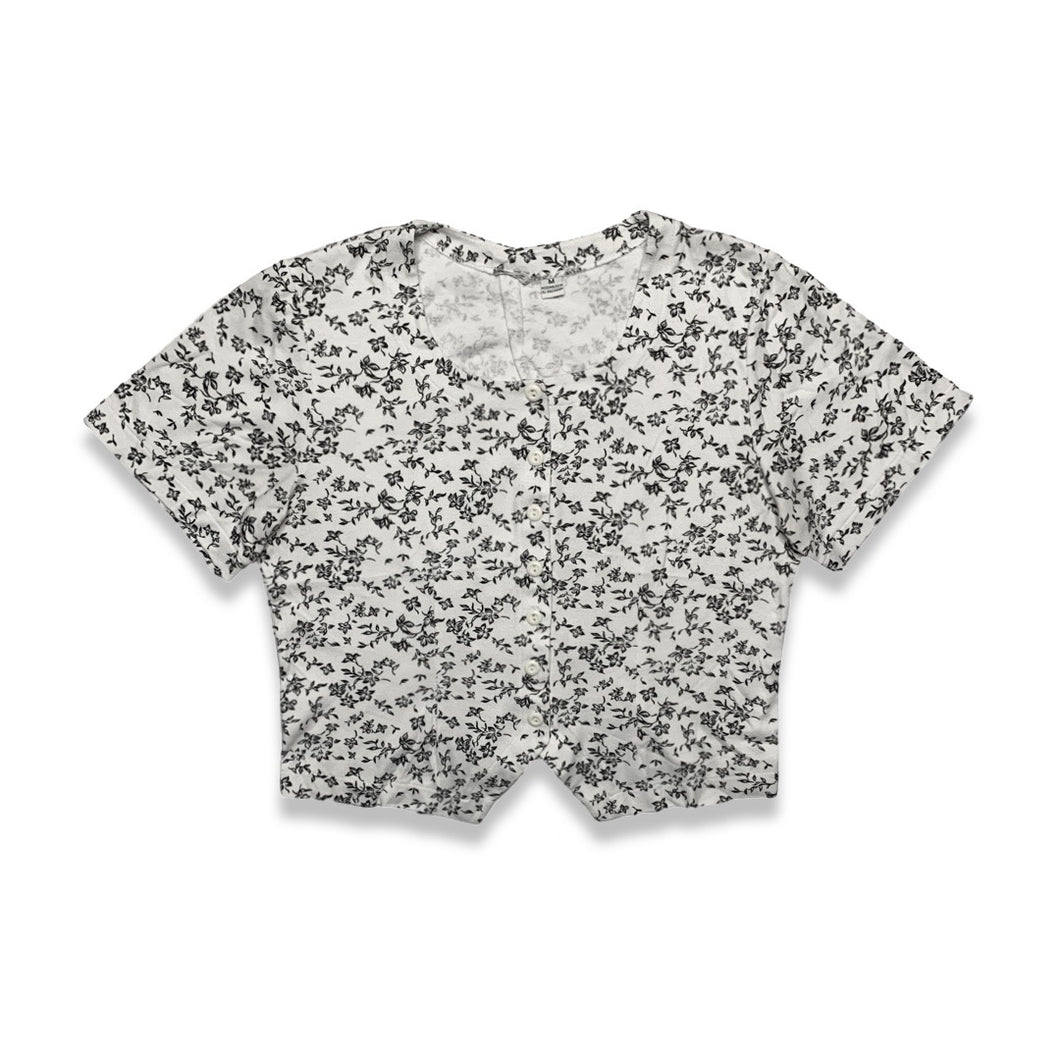 Experience a touch of nostalgia with our Vintage Black and White Floral Crop Top - the perfect blend of old and new. This short sleeve button-up piece features a chest measurement of 34